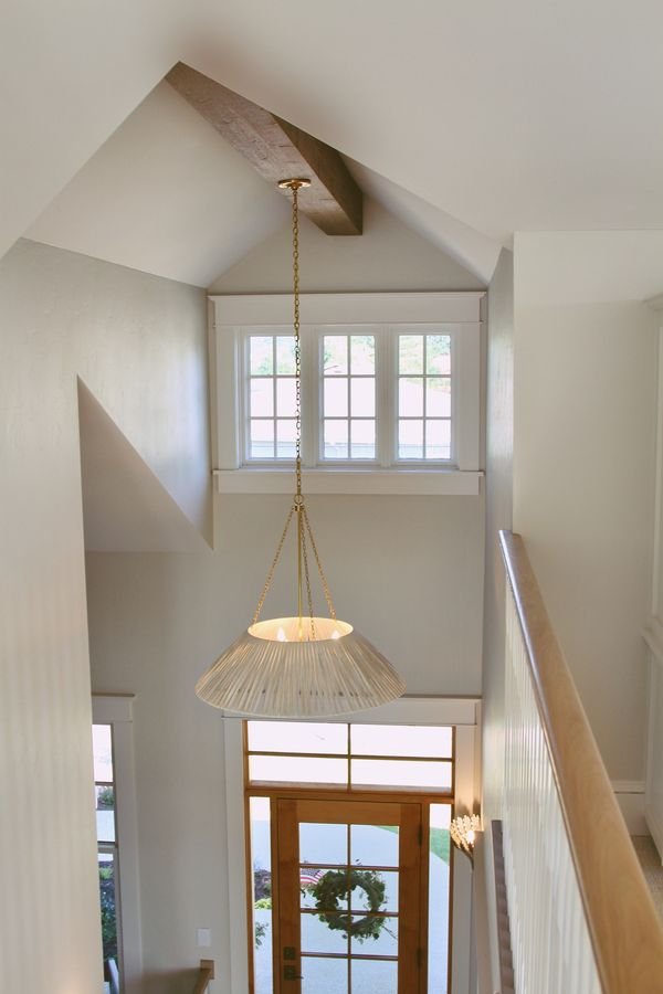 View down into the two-story entry from the upper landing, with the pendant light and wood front door below