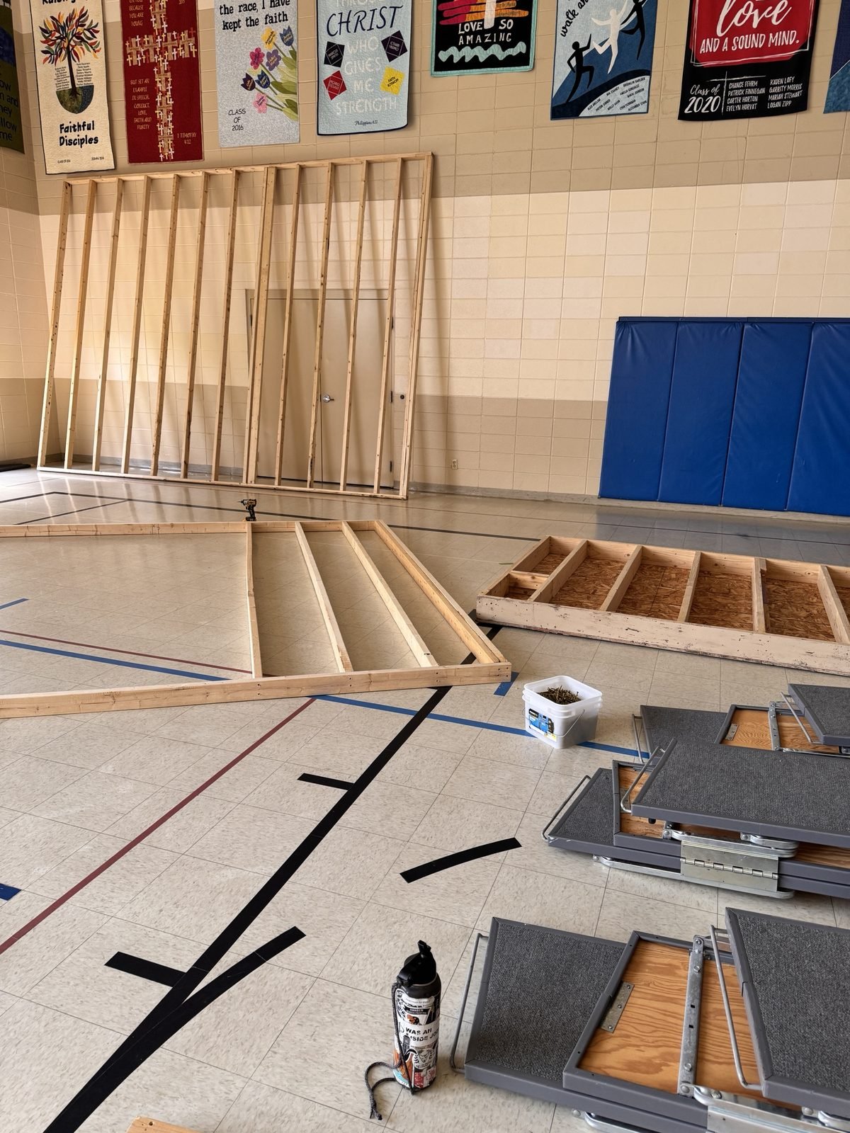 Framed walls and stage riser boxes under construction in the gym
