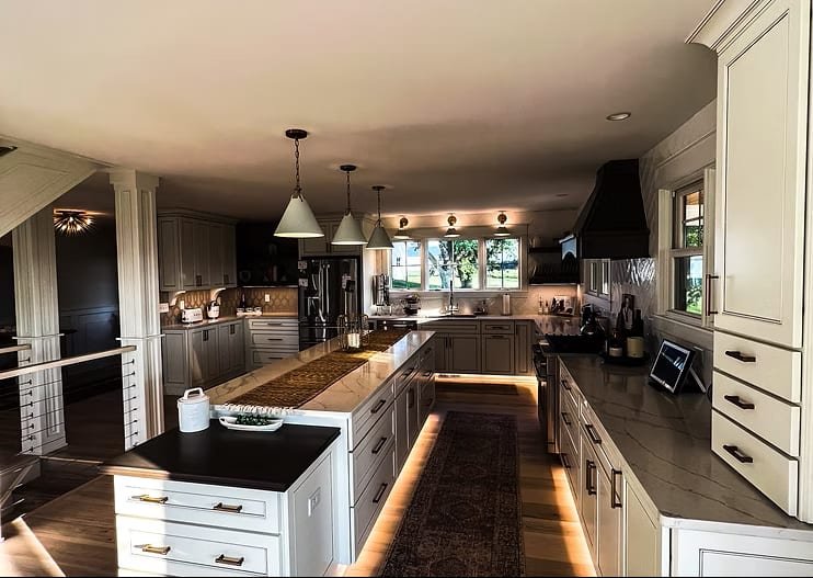 Renovated kitchen with long island, under-cabinet lighting, and two-tone cabinetry