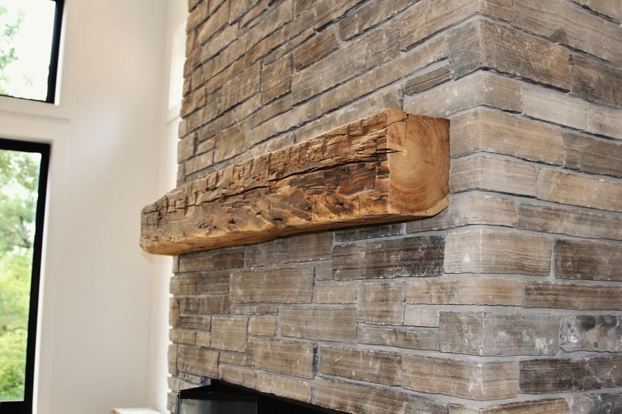 Close view of the hand-hewn timber mantel set into stacked stone