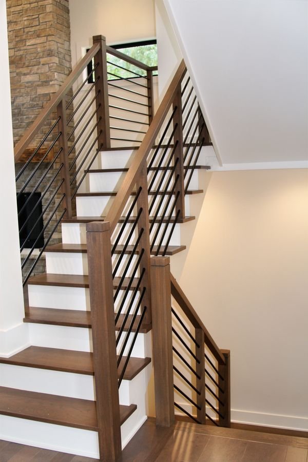 Staircase seen from below, with horizontal metal rails and the stone fireplace beyond