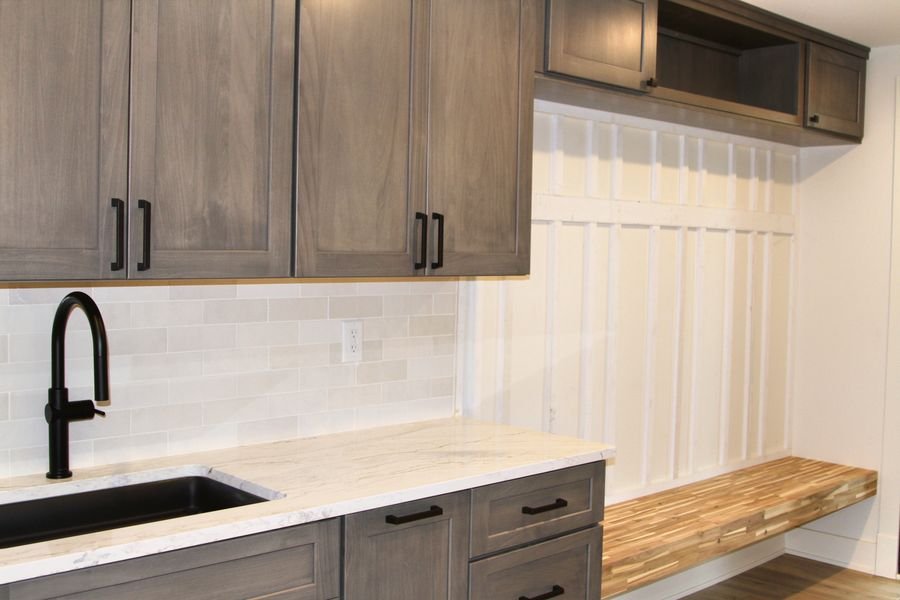 Drop zone with gray stained cabinetry, a stone countertop, and a butcher block bench