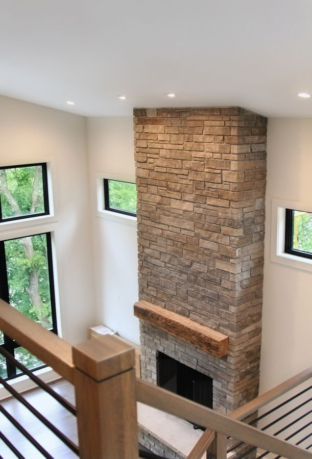 View from the stair landing down to the two-story stone fireplace and tall windows