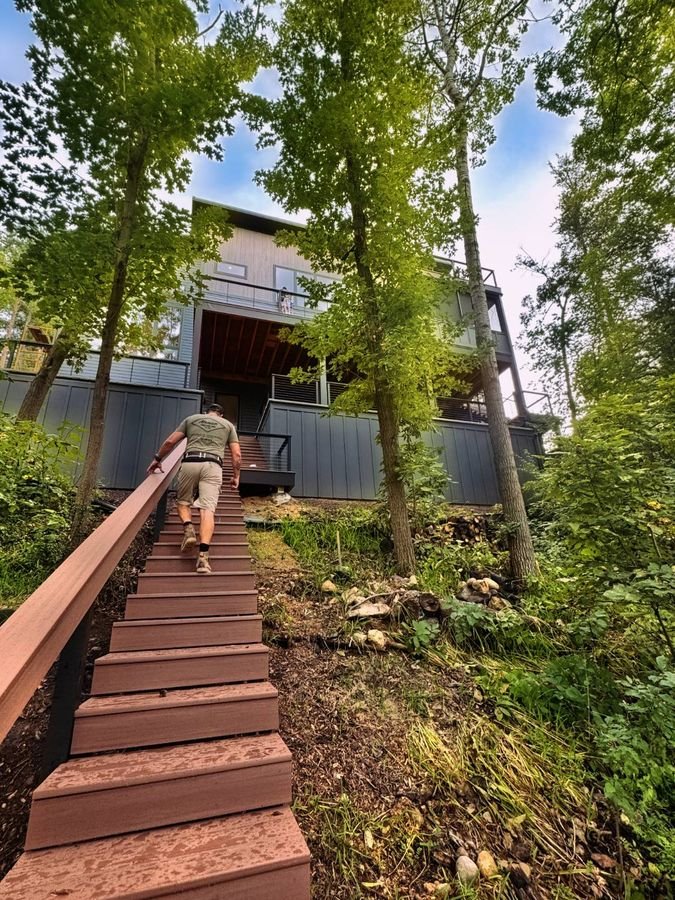 Nick Monien walking up the long lake stair toward the house among the trees